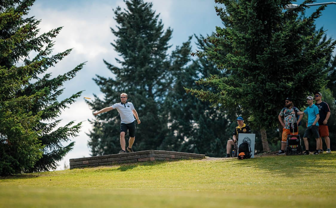 Disc Golfer throwing drive of tee. 