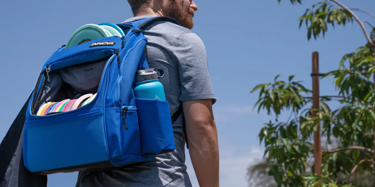 Disc golf bag with several accessories including a towel and water canteen.