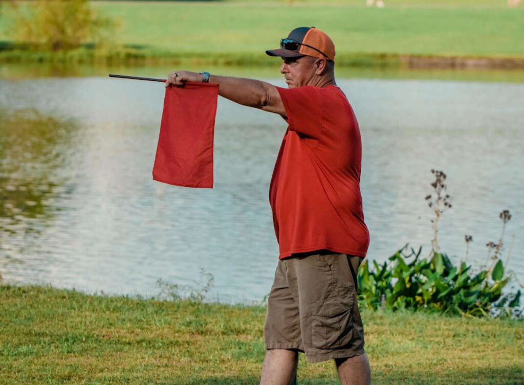 Disc Golf Rules: 5 You Should Learn. Official holding Out of Bonds flag.