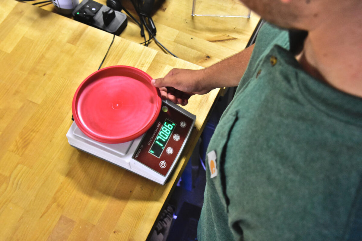 A disc golf disc being weighed on a digital scale.