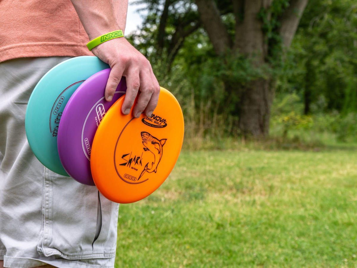 Beginner disc golfer holding an Innova starter set of discs.